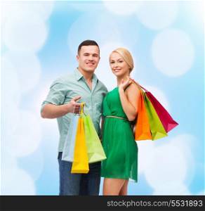 happiness, shopping and couple concept - smiling couple with shopping bags