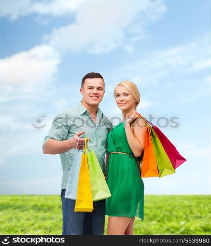 happiness, shopping and couple concept - smiling couple with shopping bags