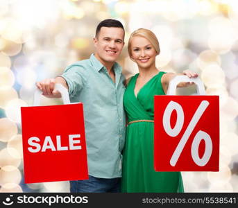 happiness, shopping and couple concept - smiling couple with shopping bags with sale and percent sign