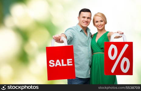 happiness, shopping and couple concept - smiling couple with shopping bags with sale and percent sign