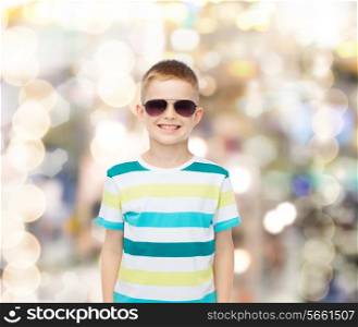 happiness, summer and people concept - smiling cute little boy in sunglasses over sparkling background