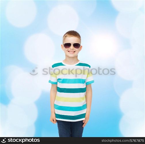 happiness, summer, childhood and people concept - smiling cute little boy in sunglasses over blue background