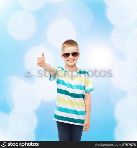 happiness, summer, childhood, gesture and people concept - smiling cute little boy in sunglasses over blue background showing thumbs up