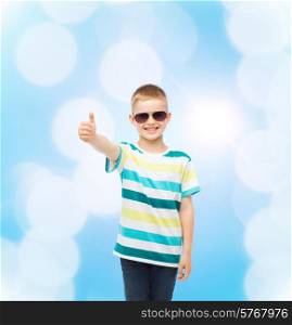 happiness, summer, childhood, gesture and people concept - smiling cute little boy in sunglasses over blue background showing thumbs up