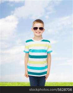 happiness, summer, childhood, nature and people concept - smiling cute little boy in sunglasses over natural background
