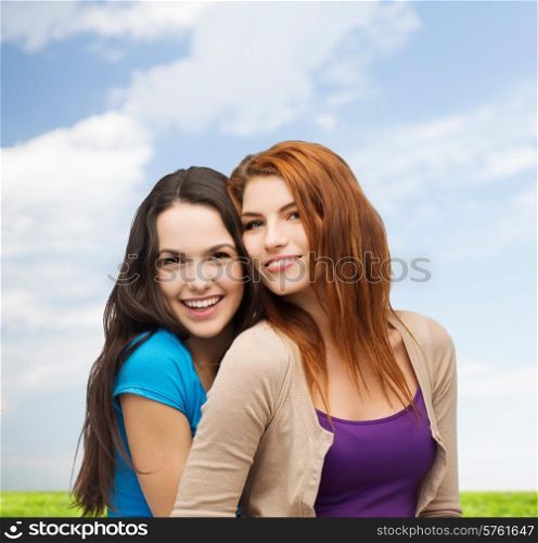 happiness, summer, friendship and people concept - smiling teenage girls hugging over blue sky and cloud background