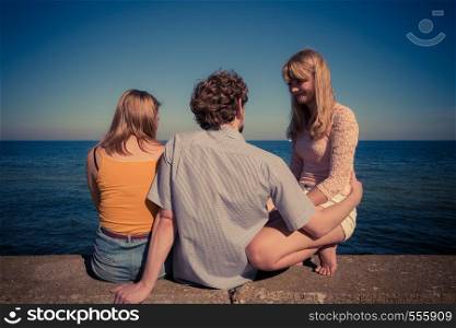 Happiness summer friendship concept. Group of friends spending time together having fun outdoor looking on sea horizon back view. Group of friends spending time together