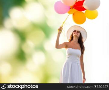 happiness, summer, holidays and people concept - smiling young woman wearing sunglasses with balloons over green background
