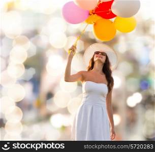 happiness, summer, holidays and people concept - smiling young woman wearing sunglasses with balloons over lights background