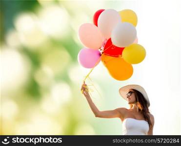happiness, summer, holidays and people concept - smiling young woman wearing sunglasses with balloons over green background