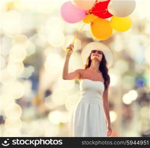 happiness, summer, holidays and people concept - smiling young woman wearing sunglasses with balloons over lights background