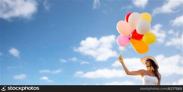 happiness, summer, holidays and people concept - smiling young woman wearing sunglasses with balloons over blue sky background