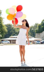 happiness, summer, holidays and people concept - smiling young woman wearing sunglasses with balloons in park