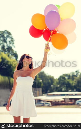 happiness, summer, holidays and people concept - smiling young woman wearing sunglasses with balloons in park