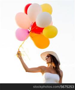 happiness, summer, holidays and people concept - smiling young woman wearing sunglasses with balloons outdoors