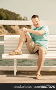 Happiness summer vacation and people concept. Fashion portrait of handsome man sitting in sun on bench sea landscape