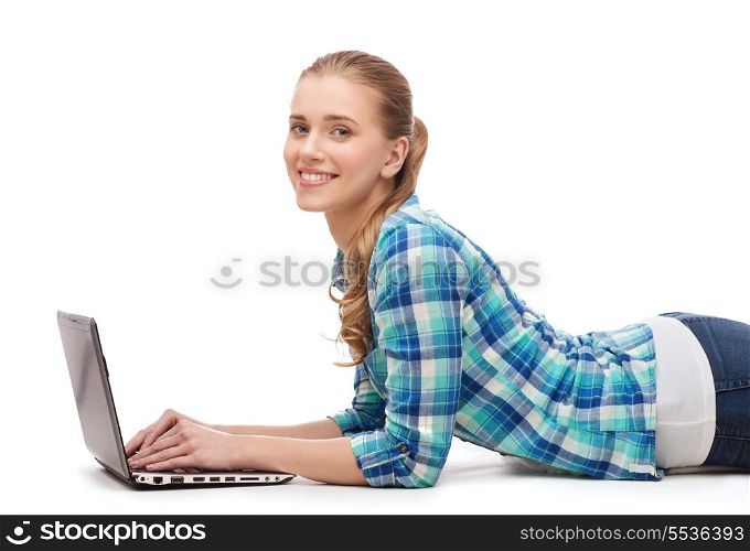 happiness, technology, internet and people concept - smiling young woman lying on floor with laptop computer