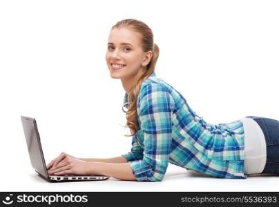 happiness, technology, internet and people concept - smiling young woman lying on floor with laptop computer