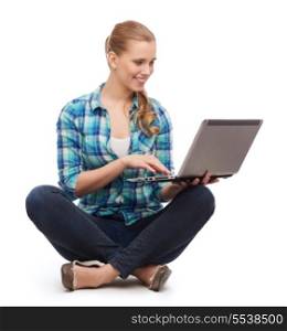 happiness, technology, internet and people concept - smiling young woman sitting on floor with laptop computer
