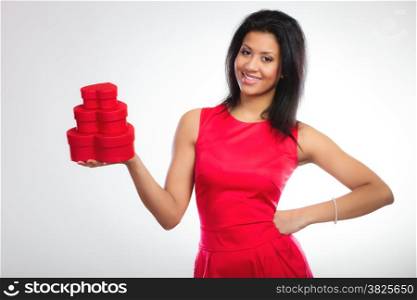 Happiness, valentines day and love concept. Attractive elegant smiling woman in red dress, girl mixed race holding red heart-shaped gift boxes on gray