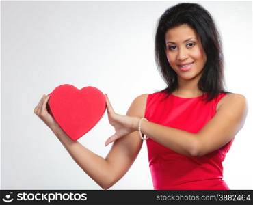 Happiness, valentines day and love concept. Lovely elegant woman in red dress, girl mixed race holding red heart-shaped gift box on gray