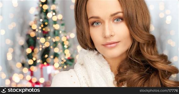 happiness, winter holidays and people concept - close up of smiling young woman in white warm clothes over christmas tree lights background