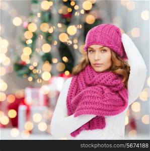 happiness, winter holidays and people concept - smiling young woman in pink hat and scarf over christmas tree with presents background