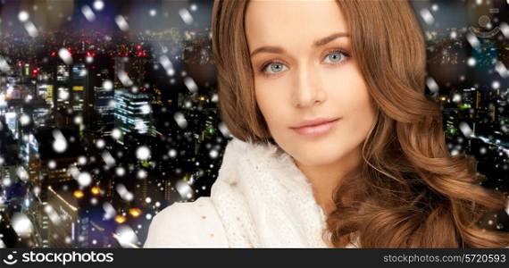 happiness, winter holidays, christmas and people concept - close up of smiling young woman in white warm clothes over snowy city background