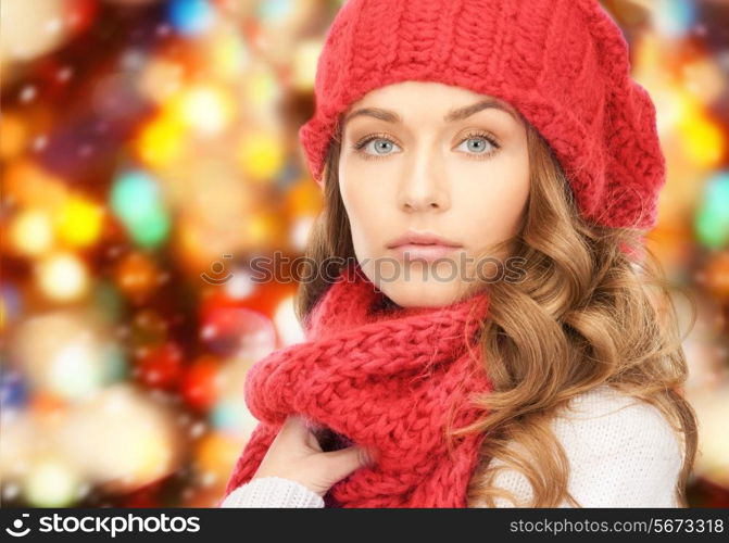 happiness, winter holidays, christmas and people concept - close up of young woman in hat and scarf over red lights background