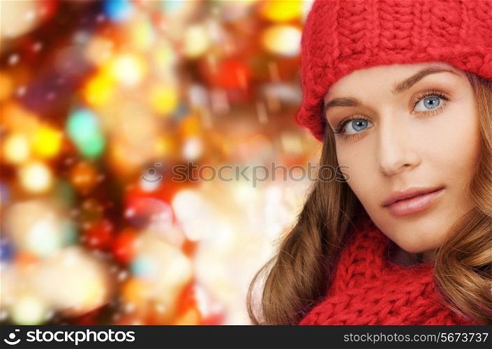 happiness, winter holidays, christmas and people concept - close up of young woman in hat and scarf over red lights background