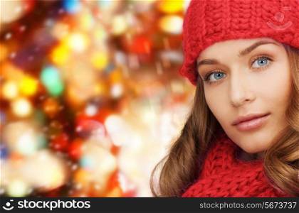 happiness, winter holidays, christmas and people concept - close up of young woman in hat and scarf over red lights background