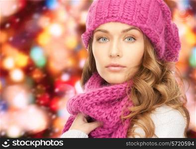 happiness, winter holidays, christmas and people concept - close up of young woman in pink hat and scarf over red lights background
