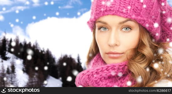 happiness, winter holidays, christmas and people concept - close up of young woman in pink hat and scarf over snowy mountains background