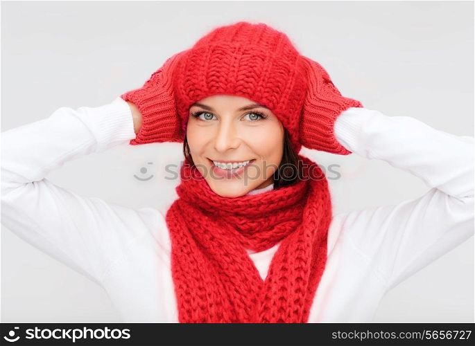 happiness, winter holidays, christmas and people concept - smiling young woman in red hat, scarf and mittens over gray background