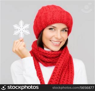 happiness, winter holidays, christmas and people concept - smiling young woman in red hat, scarf and mittens holding snowflake decoration over gray background