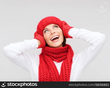 happiness, winter holidays, christmas and people concept - smiling young woman in red hat, scarf and mittens over gray background