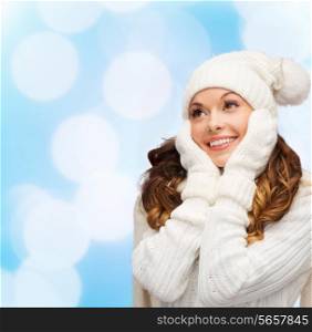 happiness, winter holidays, christmas and people concept - smiling young woman in white hat and mittens over blue lights background