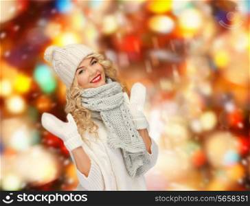 happiness, winter holidays, christmas and people concept - smiling young woman in white hat and mittens over shiny lights background