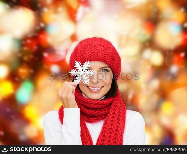 happiness, winter holidays, christmas and people concept - smiling young woman in red hat, scarf and mittens over holding snowflake red lights background