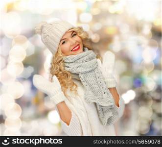 happiness, winter holidays, christmas and people concept - smiling young woman in white hat and mittens over shiny lights background