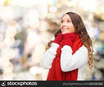 happiness, winter holidays, christmas and people concept - smiling young woman in red scarf and mittens over lights background