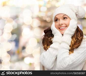 happiness, winter holidays, christmas and people concept - smiling young woman in white hat and mittens over lights background