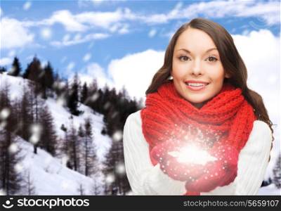 happiness, winter holidays, christmas and people concept - smiling young woman in red scarf and mittens holding snowflake over mountains background