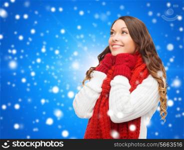 happiness, winter holidays, christmas and people concept - smiling young woman in red scarf and mittens over blue snowy background