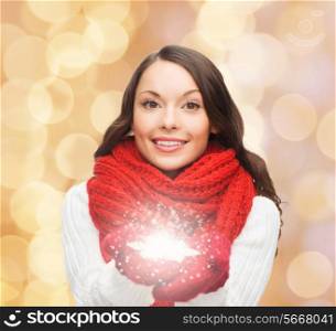 happiness, winter holidays, christmas and people concept - smiling young woman in red scarf and mittens holding snowflake over beige lights background