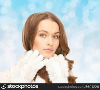 happiness, winter holidays, christmas and people concept - smiling young woman in white warm clothes over blue lights background