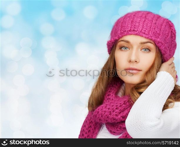 happiness, winter holidays, christmas and people concept - smiling young woman in pink hat and scarf over blue lights background