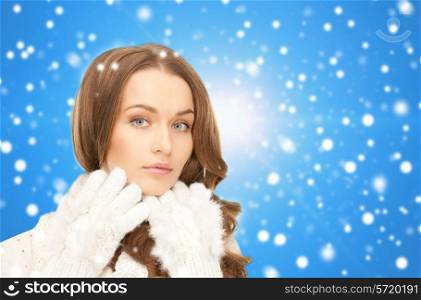 happiness, winter holidays, christmas and people concept - smiling young woman in white warm clothes over blue snowy background