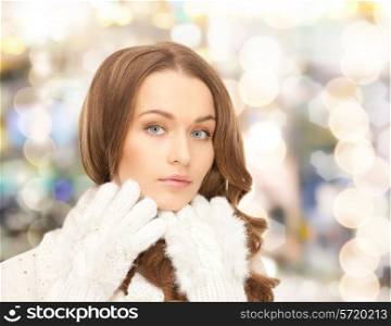 happiness, winter holidays, christmas and people concept - smiling young woman in white warm clothes over lights background