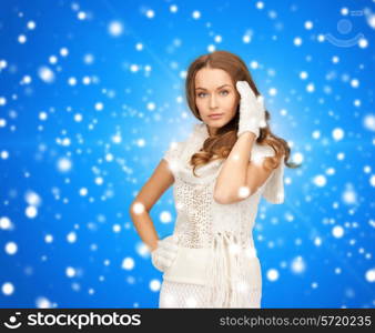 happiness, winter holidays, christmas and people concept - smiling young woman in white warm clothes over blue snowy background